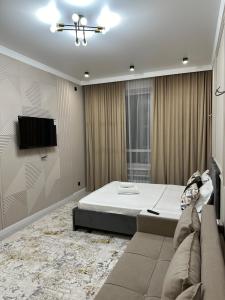 um quarto com uma cama e uma televisão na parede em HOST Apart-otel em Taldykolʼ