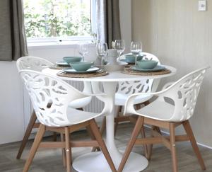 een witte eettafel met 2 stoelen en een witte tafel met glazen bij Welkom in het beachbos I Onthaasten op de Veluwe in Hoenderloo