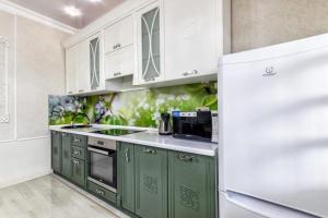 uma cozinha com armários verdes e um frigorífico branco em HOST Apart-otel em Taldykolʼ