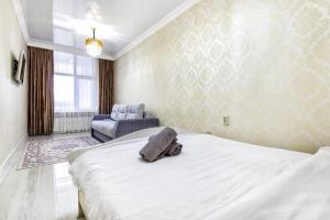 um quarto com uma grande cama branca e uma cadeira em HOST Apart-otel em Taldykolʼ