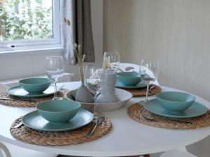 una mesa blanca con platos, tazones y copas de vino en Welkom in het beachbos I Onthaasten op de Veluwe en Hoenderloo