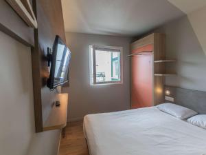 a bedroom with a bed and a flat screen tv at ibis budget Ciboure St-Jean-Luz in Ciboure