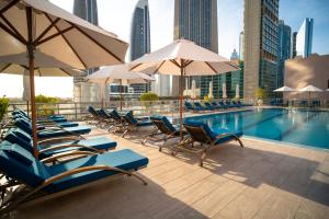 a swimming pool with lounge chairs and umbrellas at Rose Rayhaan by Rotana - Dubai in Dubai +70 photos