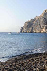 einen Strand mit einem Boot im Wasser in der Unterkunft Afroditi Venus Beach Resort in Kamari