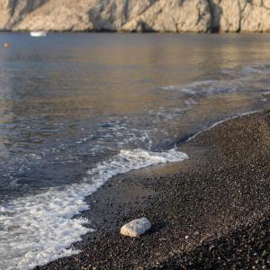 skała siedząca na plaży obok wody w obiekcie Afroditi Venus Beach Resort w mieście Kamari