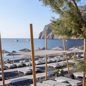 een groep ligstoelen en parasols op een strand bij Afroditi Venus Beach Resort in Kamari