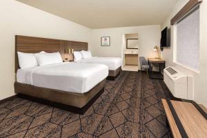 a hotel room with two beds and a desk at Ramada by Wyndham Modesto Yosemite Area in Modesto