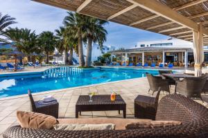um pátio exterior com uma piscina, cadeiras e uma mesa em Hotel Hara Ilios Village em Gouves