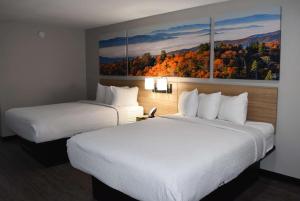 2 camas en una habitación de hotel con pinturas en la pared en Days Inn by Wyndham North Little Rock Maumelle, en Maumelle