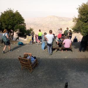 a group of people standing and sitting on benches at Jabal Dana Hotel - the highest hotel in Jordan in Dana