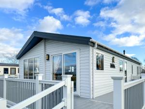 a white tiny house with a deck at Holidays with TLC at Barlings Country Park in Lincoln