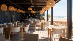 ein Restaurant mit Tischen, weißen Stühlen und Lampen in der Unterkunft T2 Miami Beach in Narbonne-Plage