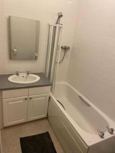 a bathroom with a sink and a bath tub and a mirror at Lovely 2 bed flat located next to Edinburgh Castle in Edinburgh
