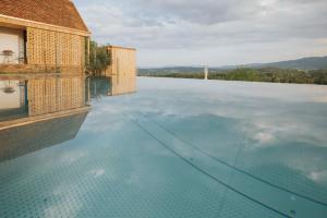 a swimming pool with blue water and a building at FRANZL - privates Refugium AmWildbachberg, mit Infinitypool, Weinkeller und Privatsauna in Deutschlandsberg