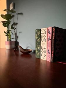 three books on a wooden table with a potted plant at Beautiful One Bed Apartment in West End Folkestone in Kent