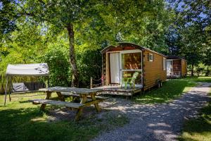 a wooden trailer with a picnic table and a tent at Auberge de la Rivière in Foncine-le-Haut