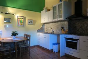 a kitchen with white cabinets and a table and a table and a dining room at Can Salgueda in Santa Pau