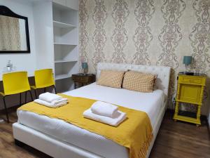 um quarto com uma cama branca e 2 cadeiras amarelas em Vintage Place - Azorean Guest House em Ponta Delgada