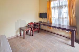 パランカラヤにあるAman Guest House Redpartnerのデスク、椅子、窓が備わる客室です。