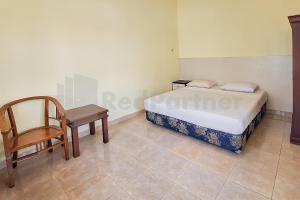 a bedroom with a bed and a chair and a desk at Aman Guest House Redpartner in Palangkaraya