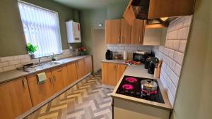 a kitchen with wooden cabinets and a stove top oven at Jasper's by Spires Accommodation a great base to stay for Alton Towers and corporate clientele working away from home in Stoke on Trent