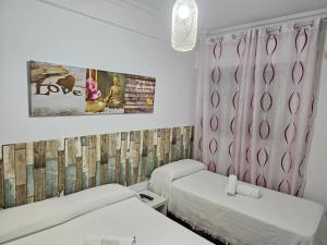 um quarto com 2 camas e uma cortina rosa em Pension Hidalgo 1 em Utrera