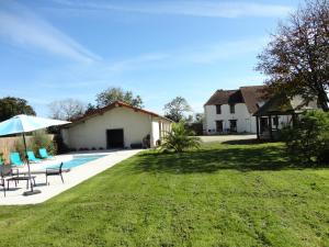a house with a pool and a yard with chairs and an umbrella at Les Grandes Landes - Piscine privée - Grand jardin in Cricqueville-en-Bessin