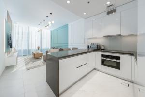 cocina con electrodomésticos blancos y sala de estar. en Dar Alsalam - Modern Comforts in Dubai District One Residence 29, en Dubái