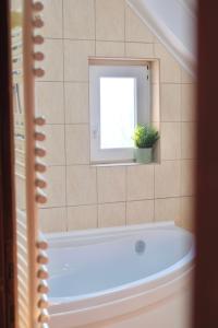 un bagno con vasca, finestra e pianta di Trón Apartman a Siklós
