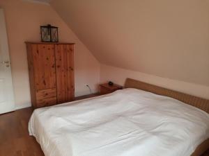 Schlafzimmer mit einem weißen Bett und einem Holzschrank in der Unterkunft Ferienhaus Landliebe, Wohnung 9048-3 in Dänschendorf