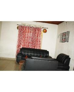 two black leather couches in a room with a curtain at GARDEN INN by AIRPORT inn ltd in Kigali