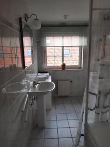 ein weißes Badezimmer mit Waschbecken und Fenster in der Unterkunft Ferienhaus Landliebe, Wohnung 9048-3 in Dänschendorf