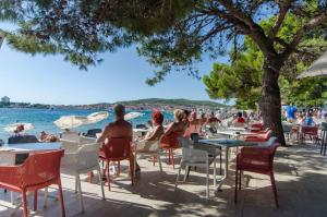 een groep mensen die aan tafels en stoelen aan het water zitten bij House Villa Whisper of nature in Vodice