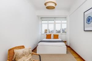 a white room with a bed and a chair at Bright and Spacious Two Bedroom Apt in Almada in Almada