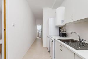 cocina blanca con fregadero y nevera en Bright and Spacious Two Bedroom Apt in Almada, en Almada