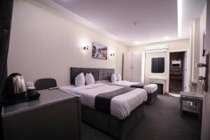 a hotel room with two beds and a desk at Hotel Royal Plaza in Asyut