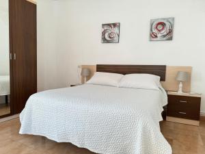1 dormitorio con 1 cama blanca y 2 cuadros en la pared en Apartamento Paseo Marítimo-A Illa de Arousa, en A Illa de Arousa