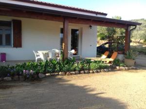 a house with a patio with chairs and flowers at La dimora del sole in Teulada +14 photos