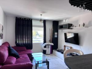 sala de estar con sofá púrpura y TV en Bahia Suite 1, en Algeciras