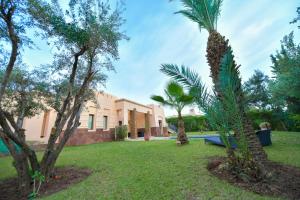 a house with a palm tree in a yard at VILLA APPLE GARDEN RESORTS 45 MARRAKECH in Marrakesh