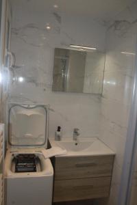 a white bathroom with a sink and a mirror at Versailles Direct : T2 Authentique et Chaleureux in Versailles