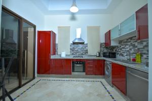 a kitchen with red cabinets and a stove top oven at VILLA APPLE GARDEN RESORTS 45 MARRAKECH in Marrakesh