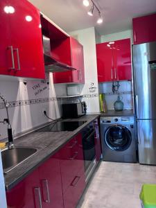 kuchnia z czerwonymi szafkami i pralką w obiekcie Bahia Suite 1 w mieście Algeciras