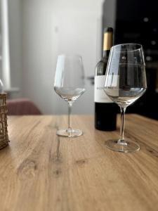 dos copas de vino sentadas sobre una mesa de madera en Modern Central Apartment en Nitra