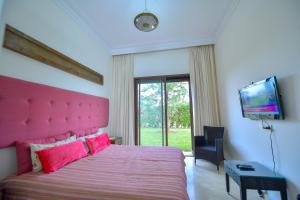 - une chambre avec un lit rose et une télévision dans l'établissement VILLA APPLE GARDEN RESORTS 45 MARRAKECH, à Marrakech