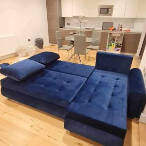 Luxury Top Floor Penthouse Apartment near Heathrow في لندن: أريكة زرقاء كبيرة في غرفة المعيشة