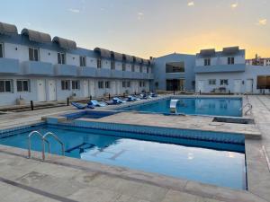 a hotel with two swimming pools in front of a building at Hotel Royal Plaza in Asyut