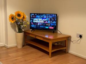 a television sitting on a table with a vase of flowers at Meadow View in Elstow