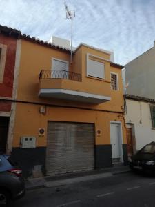 a yellow building with a garage door and a balcony at casa de tres habitaciones con parking bajo la casa in Villajoyosa
