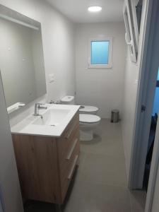 a white bathroom with a sink and a toilet at casa de tres habitaciones con parking bajo la casa in Villajoyosa